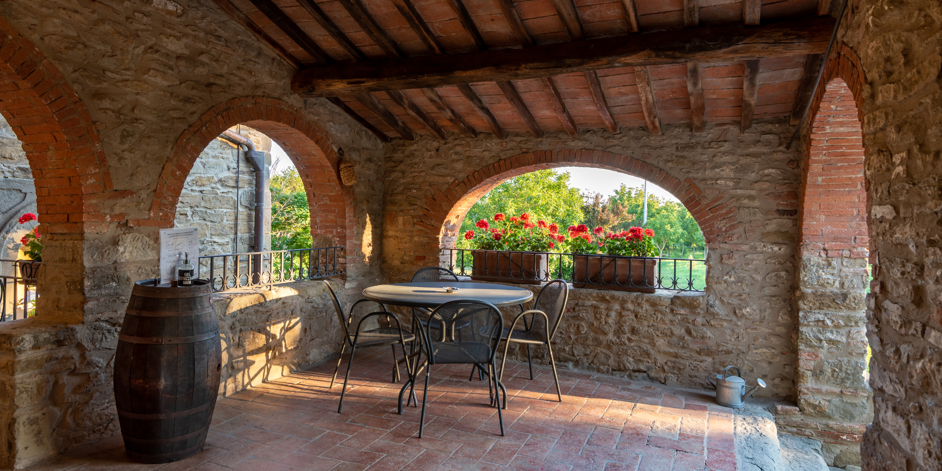 A table with chairs in the shade of an arcade, Monastero San Silvestro Farmhouse