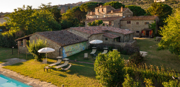 Umbrellas and loungers near the pool in the park of the ancient
									Monastero San Silvestro Farmhouse