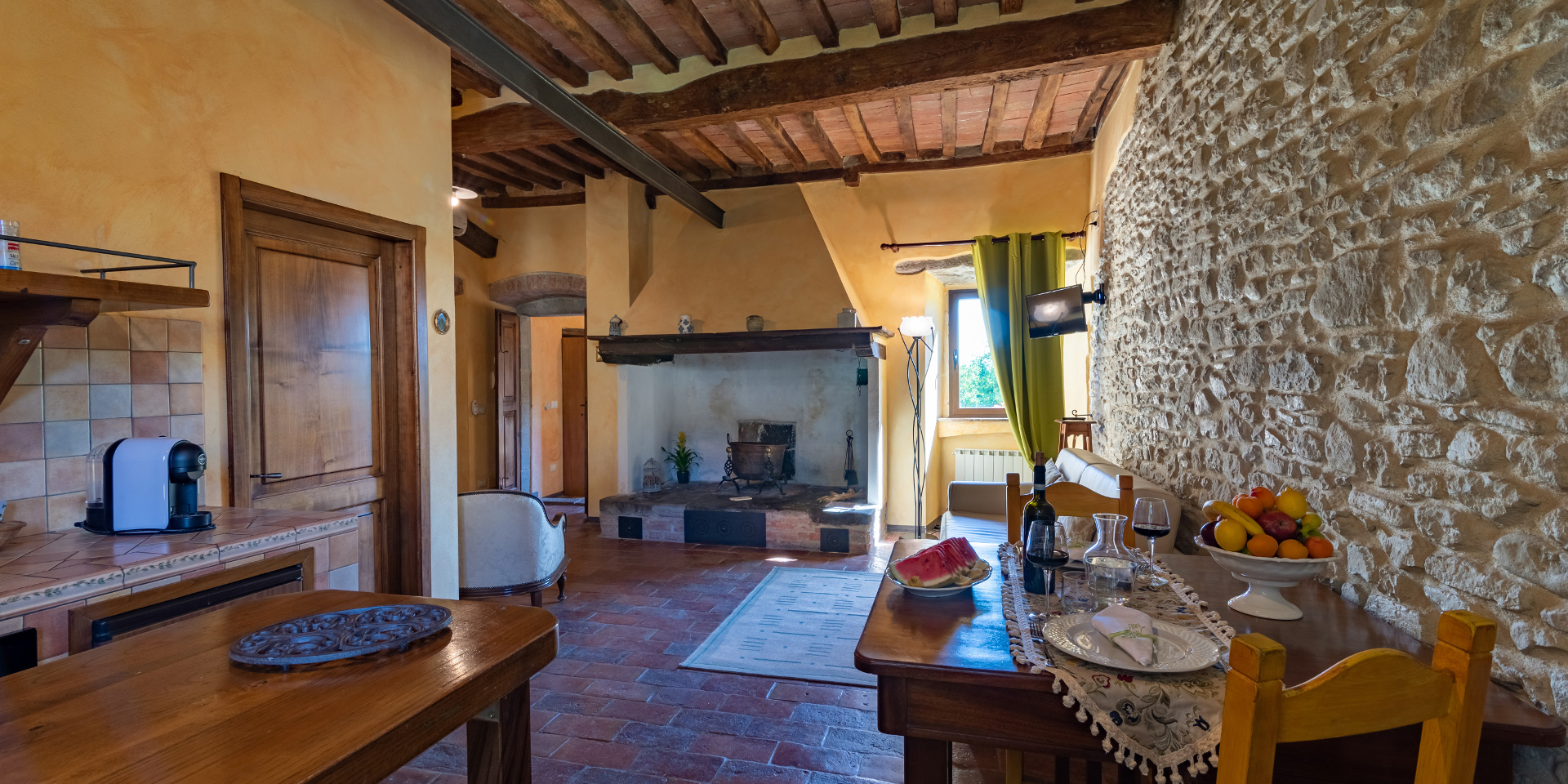 Foto del soggiorno con camino e angolo cottura
								dell’Appartamento Corito, Monastero San Silvestro