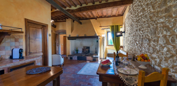 Foto in miniatura: soggiorno con camino
									e angolo cottura dell’Appartamento Corito - Monastero San Silvestro