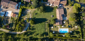 Photo from above of the park with the swimming pool in the ancient Monastero
									San Silvestro Farmhouse